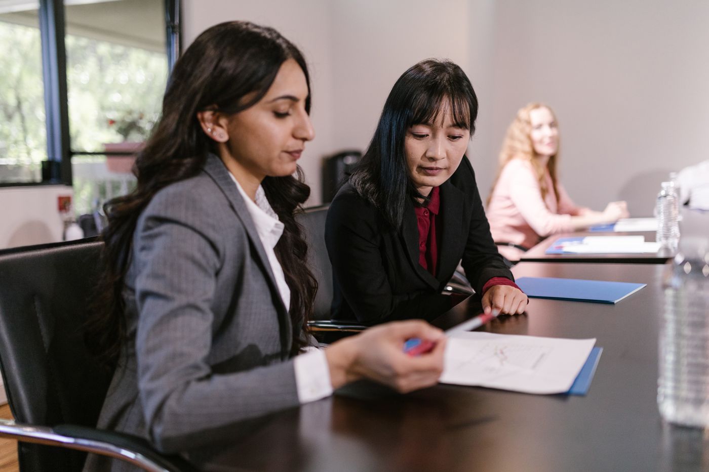 Two colleagues reviewing proposals at a meeting table